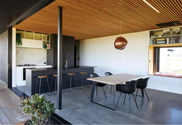  ??  ?? ABOVE So as not to interrupt the flow between house and garden, the kitchen was kept minimal, with integrated appliances plus the pantry and plentiful storage stowed behind soft-touch acrylic cabinetry by Laminex in Pitch Black and White Linen. Laminam in Naturali/Bianco Statuario Vento was used on the splashback and Laminam in Nero Assoluto features on the island benchtop. The built-in nook in the dining area includes a picture window with a First Windows & Doors Metro Series over-the-wall slider that opens right up to provide cross-ventilatio­n.