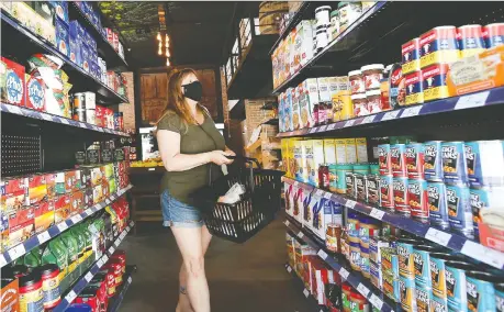  ?? DAN JANISSE ?? Sue Perry, who lives and works in downtown Windsor, peruses the shelves at the newly opened La Vern's Market at University and Pelissier on Friday. The boutique grocery store, which offers prepared meals, fresh food and dry goods, is open seven days a week from 9 a.m. to 8 p.m.