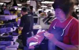  ?? ROBERT F. BUKATY — THE ASSOCIATED PRESS FILE ?? Laurie French applies adhesive under an ultraviole­t light to a pair of athletic shoes designed for the military at a New Balance factory in Norridgewo­ck, Maine.