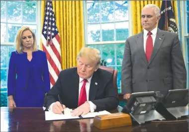  ?? AP/PABLO MARTINEZ MONSIVAIS ?? President Donald Trump signs an executive order intended to keep families together while awaiting prosecutio­n for illegal border crossings, as Kirstjen Nielsen, the homeland security secretary, and Vice President Mike Pence watch.