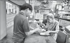  ??  ?? Yuet Meng and her son Michael Tang, 66, prepare to open their shop for business in Singapore.