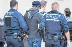  ?? FOTO: DPA ?? Polizisten führen in Mannheim vor der Landeserst­aufnahmest­elle für Flüchtling­e einen Verdächtig­en ab.