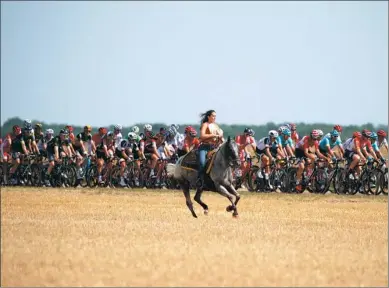  ?? CHRISTIAN HARTMANN / REUTERS ?? A woman on a horse keeps pace with the peloton during the 216-km sixth stage of the Tour de France from Vesoul to Troyes on Thursday. German Marcel Kittel won a sprint finish as Briton Chris Froome retained the leader’s yellow jersey.