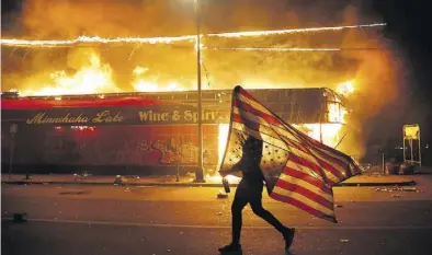  ?? Dpa-BILD: Cortez ?? Mit US-Flagge zum Protest gegen Polizeigew­alt: Mehr als 170 Geschäfte in Minneapoli­s sind bei den Krawallen in der Nacht zum Freitag zerstört oder geplündert worden.