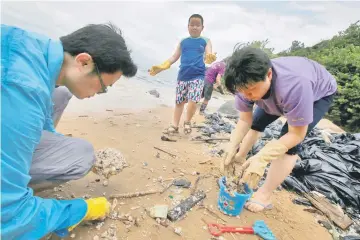  ??  ?? Volunteers collect crystallis­ed palm oil on a beach at Lamma Island in Hong Kong, China. — Reuters photo