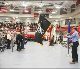  ?? ?? Farmington High student Mason Dooly presents the POW-MIA flag during a moment of silence as those attending a Veterans Day Assembly remembered soldiers who are missing in action or are prisoners of war.