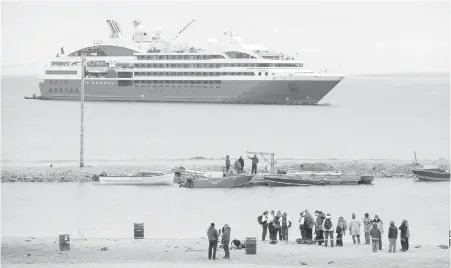  ??  ?? Passengers from a cruise ship reach the shore on zodiac boats during a visit to Gjoa Haven, Nunavut.