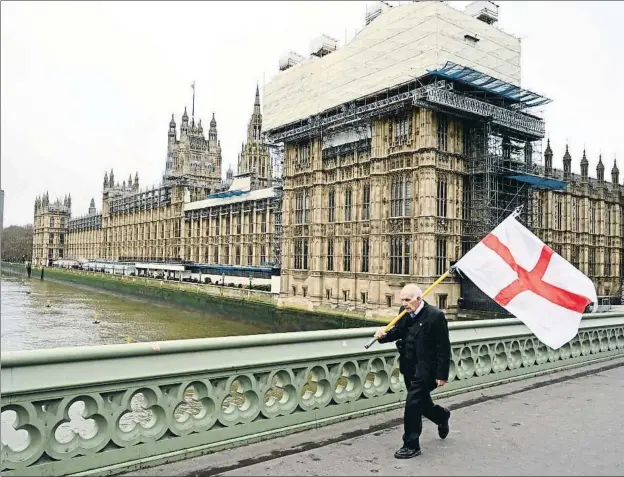  ?? GLYN KIRK / AFP ?? Un hombre cruzando el puente de Wesminster con la bandera nacional de Inglaterra pocos días antes del inicio de la pandemia