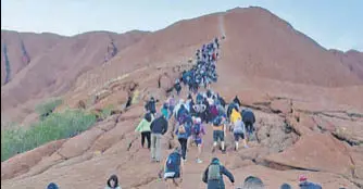  ?? AFP ?? A recent photo shows tourists climbing Uluru, also known as Ayers Rock, in Australia's Northern Territory.