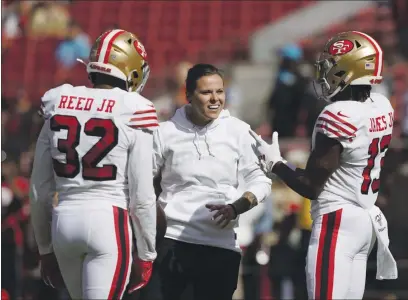  ?? TONY AVELAR — THE ASSOCIATED PRESS, FILE ?? Katie Sowers talks with 49ers free safety D.J. Reed (32) and wide receiver Richie James (13) before an October 2019 game against the Panthers in Santa Clara. Sowers served as an assistant coach for the 49ers for the last four seasons.