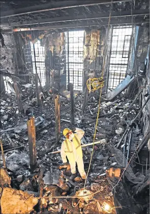  ??  ?? A forensic expert sifts through ashes of the art school library after 2014 fire