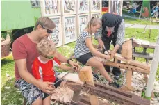  ?? FOTO: LYDIA SCHÄFER ?? Michael Reiber mit Sohn Samuel und Theresa Schlepp hobeln im mobilen Museum Holzschind­eln.