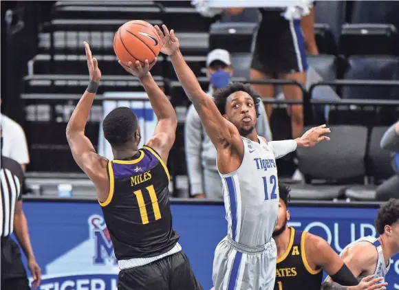  ?? JUSTIN FORD/USA TODAY SPORTS ?? Memphis forward Deandre Williams (12) tries to deflect a shot by East Carolina guard J.J. Miles (11) during their Feb. 6 game. The Tigers’ defense is allowing just 62.3 points per game this season. That figure dropped to 60.8 points over the past 11 games.