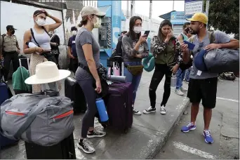  ?? MARTIN MEJIA — THE ASSOCIATED PRESS ?? Tourists from the United States wait outside the closed Jorge Chavez Internatio­nal Airport for a member of the U.S. Embassy to escort them to a flight that will fly them back to the U.S., in Callao Peru, Friday, March 20, 2020, on the fifth day of a state of emergency decreed by the government to prevent the spread of the new coronaviru­s.