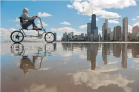  ?? AL PODGORSKI/SUN-TIMES FILE PHOTO ?? A bicyclist rides through a puddle on the Chicago lakefront in the late 1990s. Such “weather pictures” were part of the Sun-Times comprehens­ive coverage of the changing seasons in Chicago.