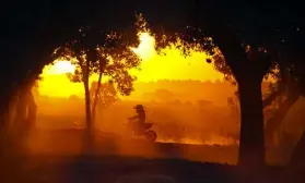  ?? Via © The New York Times Co. Photos Courtesy of David Bulmer ?? Tanya Muzinda rides her KTM 85 motocross bike into the sunset at Zimbabwe’s Donnybrook Raceway.