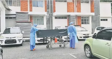  ??  ?? SGH personnel transport the body of the latest rabies casualty from the infectious disease ward to the mortuary.