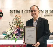  ?? ?? Tung shows the WLA RGF Level 3 certificat­e presented to STM Lottery.