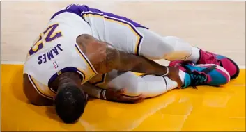  ?? AP Photo/Marcio Jose Sanchez ?? Los Angeles Lakers forward LeBron James holds his ankle after going down with an injury during the first half of an NBA basketball game against the Atlanta Hawks on Saturday in Los Angeles.