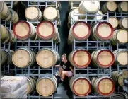  ?? PHOTO: REUTERS ?? Savannah Peterson, a trainee winemaker and daughter of owner Colin Peterson, sits between barrels of wine.