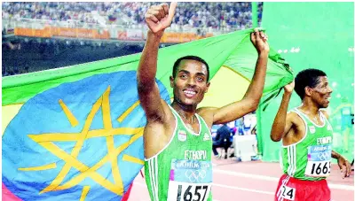  ?? FILE ?? Gold-medal winner Kenenisa Bekele of Ethiopia (left) celebrates with compatriot Haile Gebrselass­ie, who placed fifth, during a victory lap after the 10,000m at the 2004 Olympic Games on Friday, August 20, in Athens, Greece.