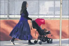  ?? KATHY WILLENS — THE ASSOCIATED PRESS ?? A woman walks with a child, Sunday, Oct. 4, through the Borough Park neighborho­od of New York, one of nine ZIP codes to have recently seen a rise in cases of coronaviru­s. New York City’s mayor said Sunday that he has asked the state for permission to close schools and reinstate restrictio­ns on nonessenti­al businesses in several neighborho­ods because of a resurgence of the coronaviru­s.