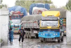  ?? — Reuters ?? An Afghan security guard stands while supply trucks carry containers for export at the Customhous­e in Jalalabad, Afghanista­n.