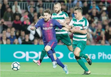  ?? — AFP ?? Barcelona’s forward from Argentina Lionel Messi (L) runs with the ball besides Eibar’s defender from Spain David Junca (C) during the Spanish league match at the Camp Nou Stadium in Barcelona.