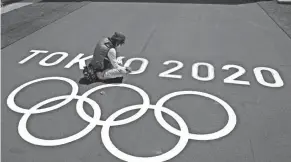  ?? CHARLIE RIEDEL/AP ?? A worker paints Olympic rings at the finish line of the BMX racing track Tuesday during preparatio­ns for the 2020 Summer Olympics in Tokyo.