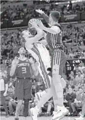  ??  ?? Heat forward Kelly Olynyk is stopped at the basket by Hornets center Frank Kaminsky in the first half Sunday.