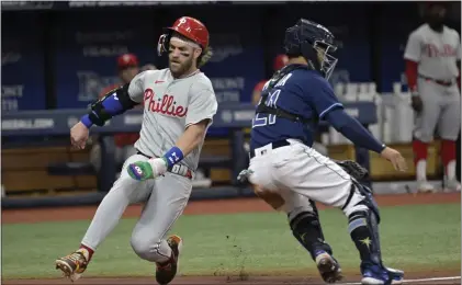  ?? STEVE NESIUS — THE ASSOCIATED PRESS ?? The Phillies’ Bryce Harper, left, beats the throw to Tampa Bay catcher Francisco Mejia to score on J.T. Realmuto’s single during the third inning on Wednesday in St. Petersburg, Fla.