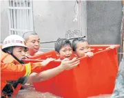  ?? AFP ?? Rescuers evacuate young residents through floodwater­s brought by Typhoon Megi in Ningde, Fujian province, China.