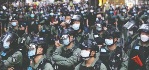  ?? EPA / JEROME FAVRE ?? Thousands of Chinese citizens, top, attend a flash mob to celebrate the National Day of the People's Republic of China on Thursday. But in Hong
Kong, bottom, police stand guard during a banned rally on Thursday, as Beijing has clamped down on protests in the former British colony.