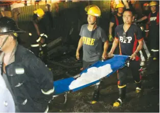  ??  ?? FATALITY – The body of one of the six victims is taken out of the gutted building in Parañaque Wednesday night. (Manny Llanes)