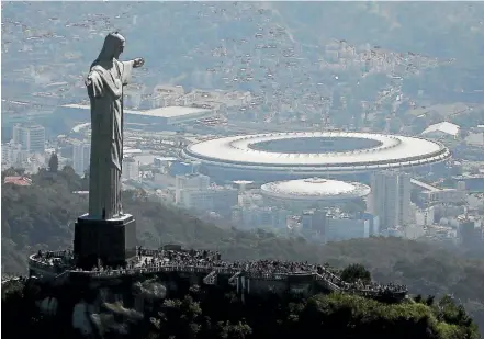  ?? PHOTO: GETTY IMAGES ?? Visitors gather beneath the Christ the Redeemer statue with Maracana stadium, site of the Olympic opening ceremonies, in the background.