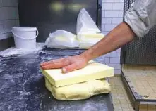  ?? AP ?? A baker works a slab of butter at a Paris bakery. French pastries and butter have become so popular abroad that the increased demand led to a mini shortage of the dairy product in French supermarke­ts.