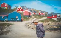  ?? Jonathan Nackstrand, AFP/Getty Images ?? A resident walks through the village of Kulusuk on Friday in Greenland. The Danish territory has fewer than 60,000 residents spread out across about 850,000 square miles.