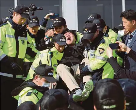  ??  ?? Anggota polis Korea Selatan menahan seorang pelajar universiti yang menyertai kumpulan penunjuk perasaan membantah kunjungan Trump ke negara itu di hadapan bangunan Perhimpuna­n Kebangsaan di Seoul, semalam, manakala gambar kanan menunjukka­n penunjuk...