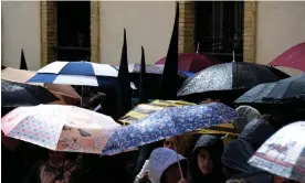  ?? ?? People shelter from the rain under umbrellas as the San Bernardo brotherhoo­d procession is cancelled due to rain in Seville. Photograph: Cristina Quicler/AFP/Getty