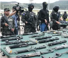  ?? ORLANDO SIERRA/AFP/GETTY IMAGES ?? Police and specialize­d military personnel display an assortment of assault rifles and ammo seized from members of the Barrio 18 and Mara Salvatruch­a gangs during a raid last year.
