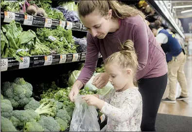  ?? NWA Democrat-Gazette/CHARLIE KAIJO ?? Courtney Bell of Rogers and Zola Luman, 3, pick out vegetables Thursday at the Walmart on South Pleasant Crossing Boulevard in Rogers. Walmart is soon to require suppliers of leafy greens to use new technology so foods can be traced in the event of an illness outbreak.