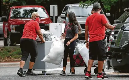  ?? Gerry Broome / Associated Press ?? Families help college students move in for the fall semester at North Carolina State University in Raleigh on July 31. The first wave of college students returning to their dorms hasn’t found the typical mobs because of COVID-19 restrictio­ns.