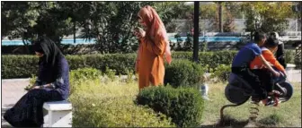  ?? ?? Afghan women look at their cellphones as children play.