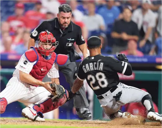  ?? DREW HALLOWELL/GETTY IMAGES ?? Leury Garcia slides past Phillies catcher J.T. Realmuto to score the go-ahead run in the 15th inning Friday night at Citizens Bank Park.