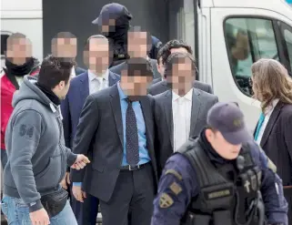  ??  ?? Eight Turkish military officers, who fled to Greece on a helicopter in July following a failed coup in Turkey, are escorted by police officers to Greece’s Supreme Court yesterday. The decision not to extradite them is irreversib­le.