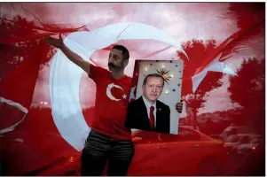  ?? AP/EMRAH GUREL ?? A man holds a picture of Recep Tayyip Erdogan, Turkey’s president and ruling Justice and Developmen­t Party leader, while celebratin­g outside the party headquarte­rs Sunday in Istanbul.