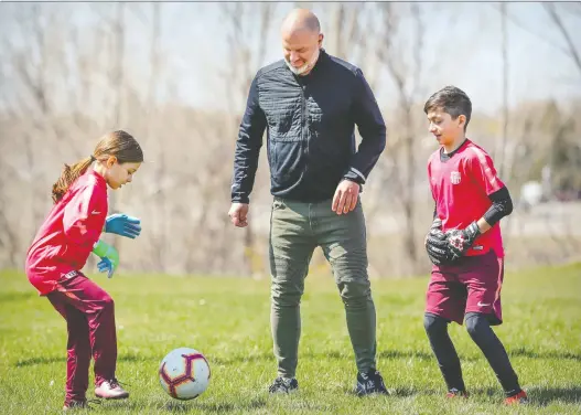  ?? JOHN MAHONEY ?? Mike Smith kicks a soccer ball with children Sofya and James in Laval on Wednesday. Smith lost $2,600 after a soccer academy associated with a Spanish club was cancelled.