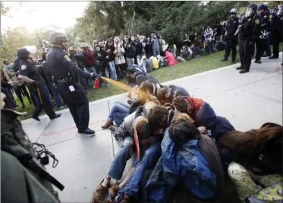  ?? WAYNE TILCOCK — DAVIS ENTERPRISE VIA AP ?? UC Davis Police Lt. John Pike uses pepper spray to move Occupy UC Davis protesters while blocking their exit from the school’s quad in Davis.