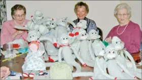  ??  ?? The Craft Group convenes each Wednesday afternoon to knit, stitch and sew items for the annual craft fair in held in November. Here they are with their family of sock monkeys. Mary Homer photo.