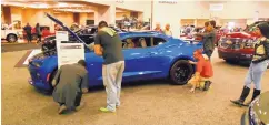  ??  ?? Eventgoers check out a striking blue sports car at a New Mexico Internatio­nal Auto Show.